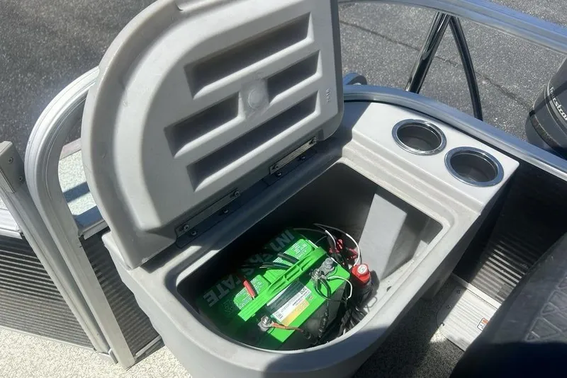 Slide: The Image of Open storage compartment on 2021 Bennington 20 SFX boat, revealing a green marine battery. - 5
