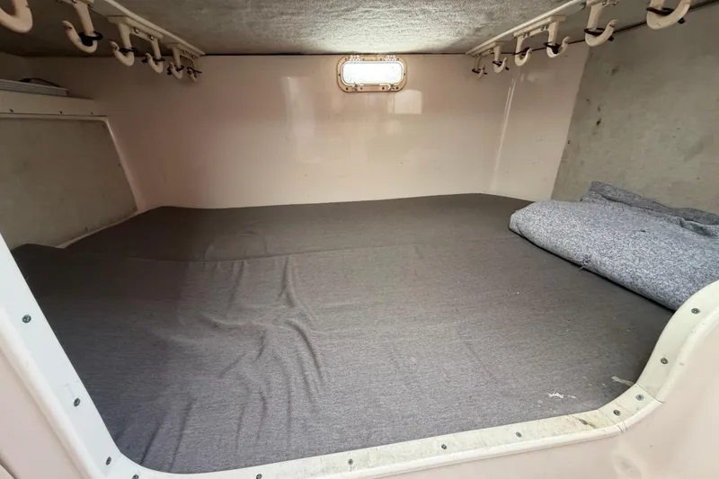 Slide: The Image of 1996 Grady-White Marlin 300 cabin interior with gray bedding and storage hooks. - 19