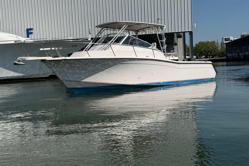 Slide: The Image of 1996 Grady-White Marlin 300 boat docked on calm water near a marina. - 3