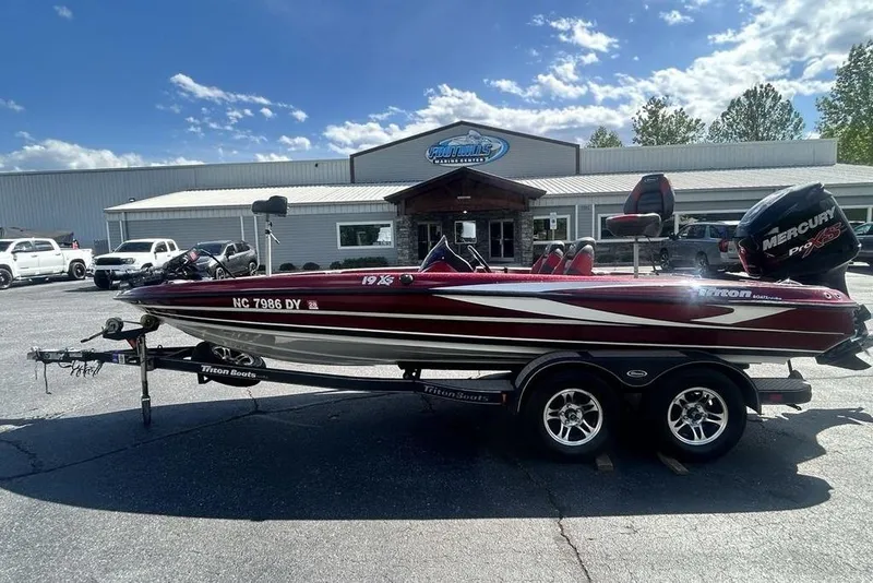 The Image of 2014 Triton 19XS boat on trailer, parked outside dealership under a clear blue sky. - 1