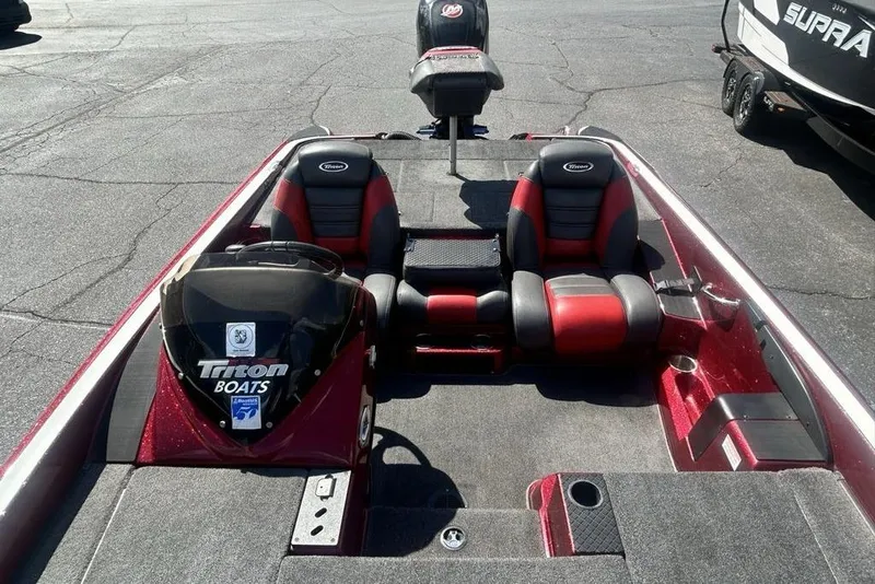 Slide: The Image of 2014 Triton 19XS boat interior with red and black seating, parked on asphalt. - 11