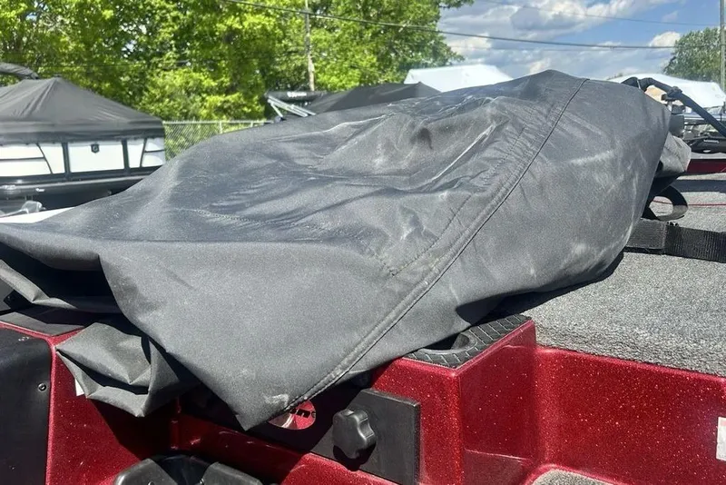 Slide: The Image of 2014 Triton 19XS boat with a black cover, outdoors on a sunny day. - 12