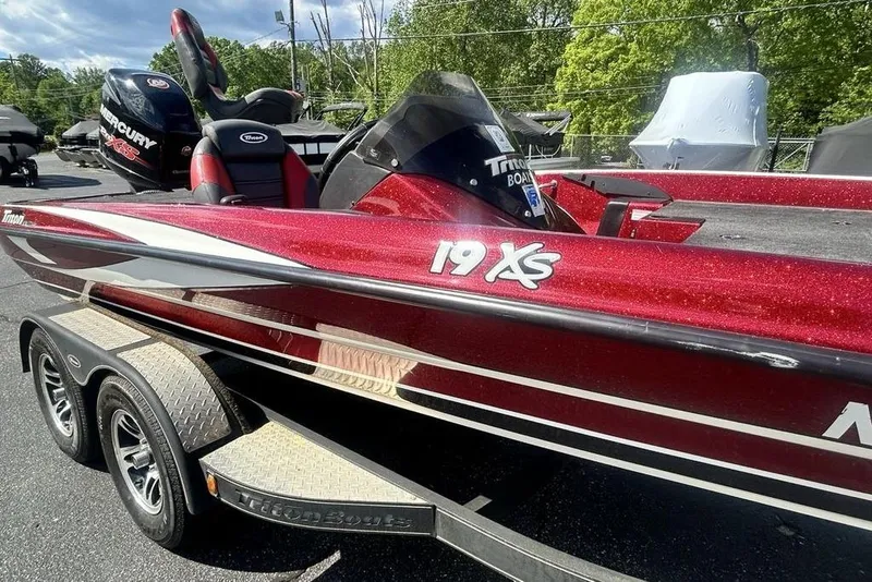 Slide: The Image of 2014 Triton 19XS boat with red finish on a trailer, parked outdoors. - 3