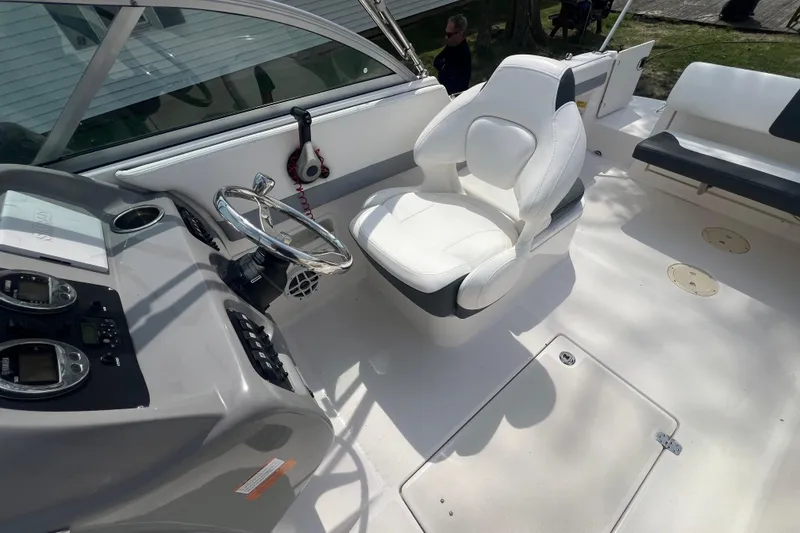 Slide: The Image of 2022 Robalo R227 Dual Console boat interior with steering wheel and white captain's chair. - 22