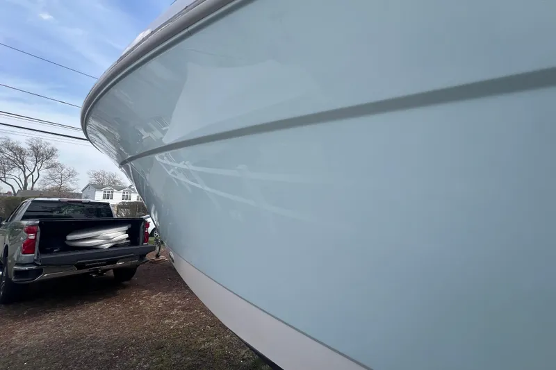 Slide: The Image of 2022 Robalo R227 Dual Console boat beside a parked truck outdoors. - 3