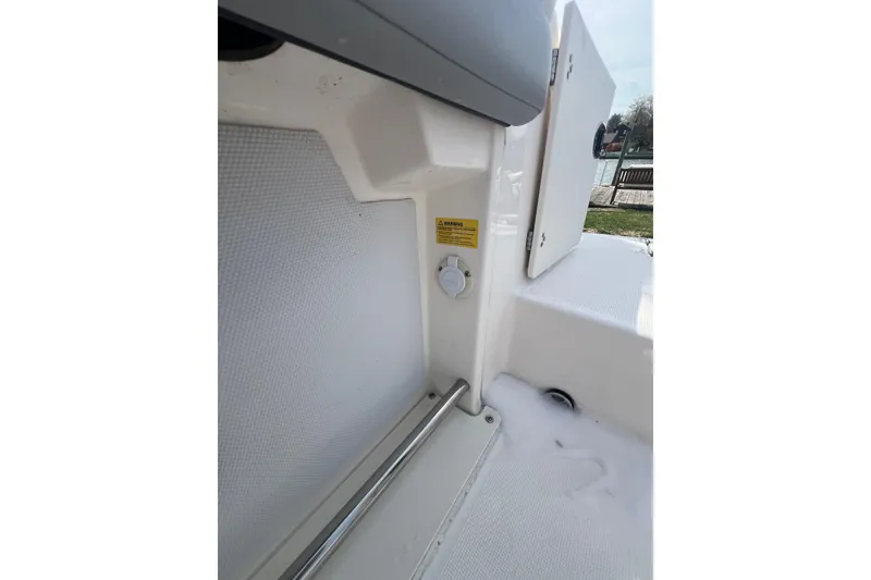 Slide: The Image of 2022 Robalo R227 Dual Console interior detail with storage compartment and safety warning label. - 40