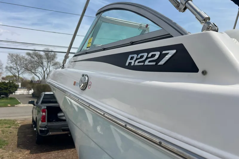 Slide: The Image of 2022 Robalo R227 Dual Console boat, side view with logo, parked outdoors. - 54