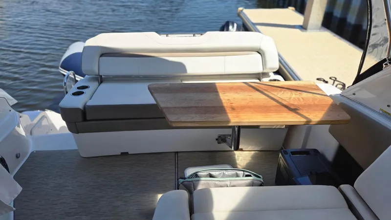 Slide: The Image of 2017 Regal 32 Express boat interior with seating and wooden table by the water. - 4