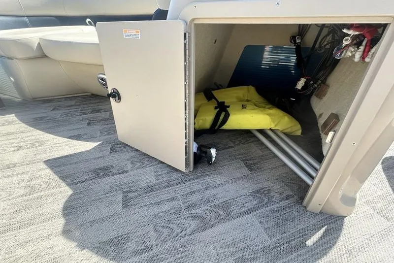 Slide: The Image of Open storage compartment on 2018 Manitou Aurora LE 22 RF boat, showing interior items. - 15
