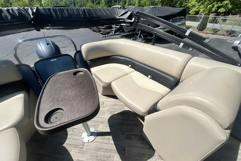 Slide: The Image of 2018 Manitou Aurora LE 22 RF boat interior with beige seating and a wooden table. - 19