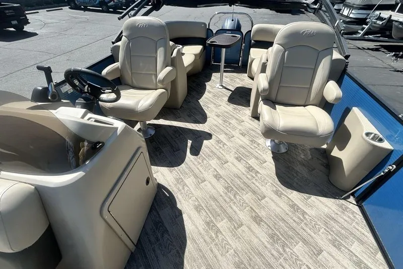 Slide: The Image of 2018 Manitou Aurora LE 22 RF Twin Tube boat interior with beige seating and steering console. - 6