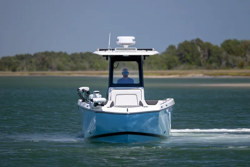 Slide: The Image of 2025 Yamaha Boats 255 FSH Sport H cruising on a serene lake with lush greenery. - 7