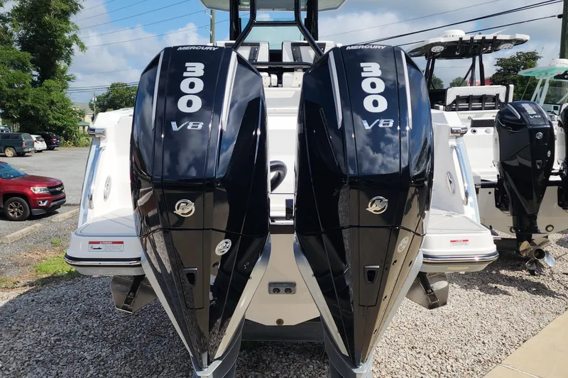 Slide: The Image of 2026 Blackfin 272 CC boat with dual Mercury 300 V8 engines, parked outdoors. - 2