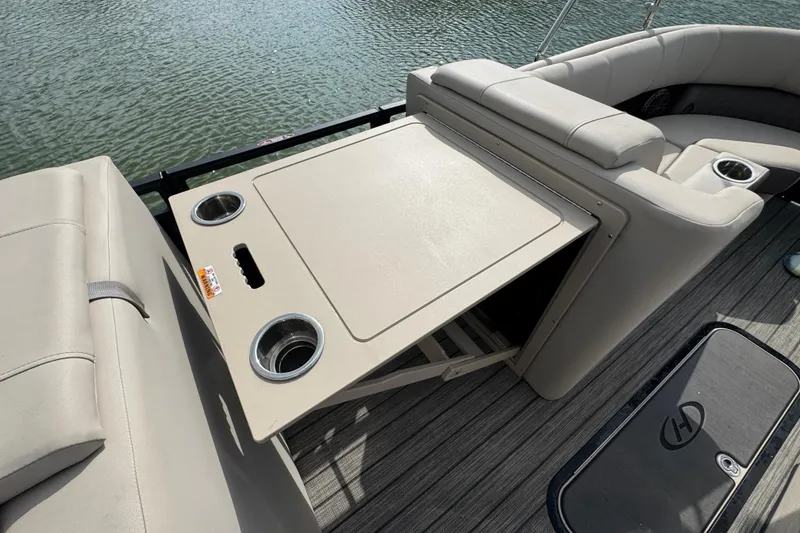 Slide: The Image of 2021 Harris Solstice 230 boat interior with seating and cup holders on a sunny day. - 21