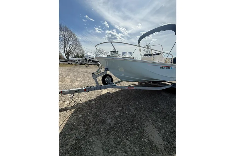 Slide: The Image of 2025 Boston Whaler 190 Montauk boat on trailer under a partly cloudy sky. - 13