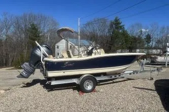 Slide: The Image of 2024 Scout 195 Sport Dorado boat on trailer, parked outdoors. - 2