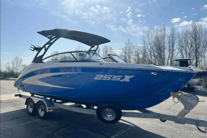 The Image of 2025 Yamaha Boats 255XD in blue on a trailer, parked outdoors. - 1