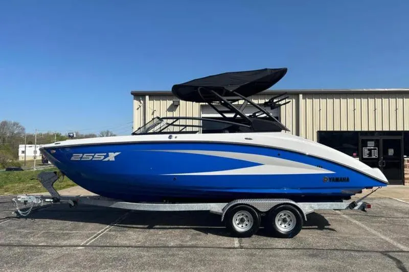 Slide: The Image of 2025 Yamaha Boats 255XD in blue on trailer, parked outdoors. - 3