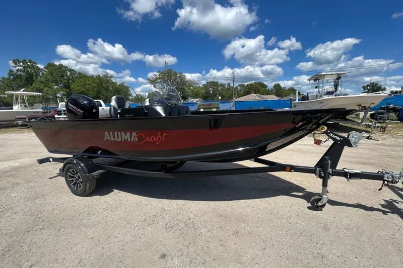 The Image of 2023 Alumacraft Competitor 165 SC boat on trailer under a clear blue sky. - 1