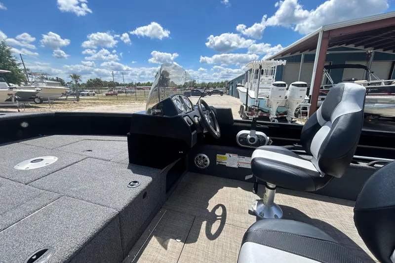 Slide: The Image of 2023 Competitor 165 SC boat interior with steering console and seating under a blue sky. - 14