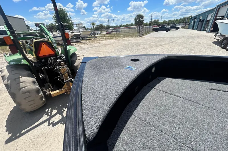 Slide: The Image of 2023 Competitor 165 SC boat near green tractor in outdoor storage area. - 16