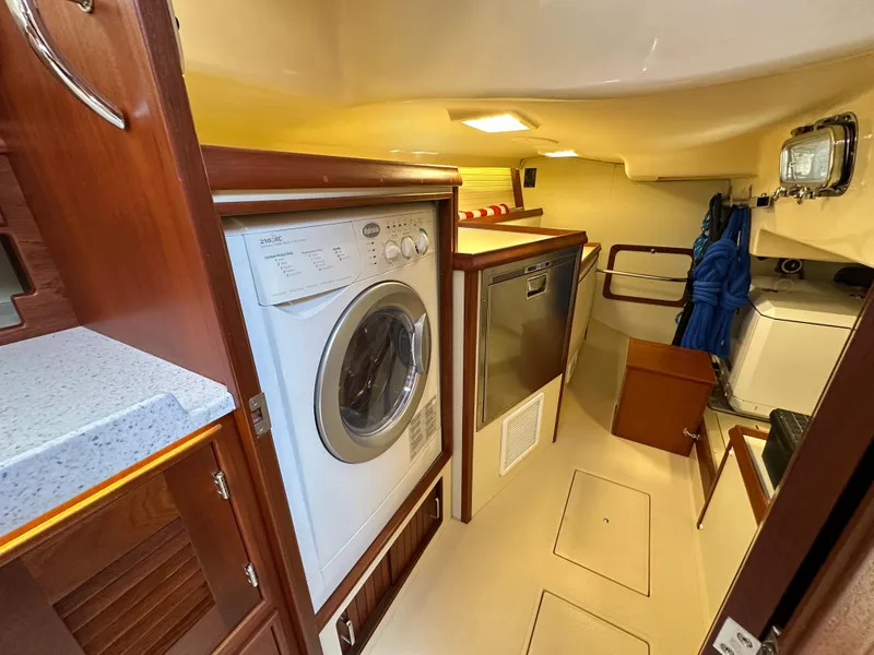 Slide: The Image of Laundry area inside 2021 Island Packet 439 yacht, featuring washer, dryer, and storage space. - 33