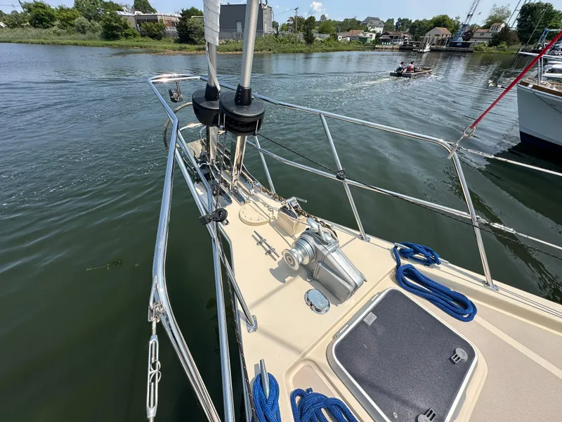 Slide: The Image of Bow of 2021 Island Packet 439 sailboat with anchor and ropes on a calm waterway. - 8