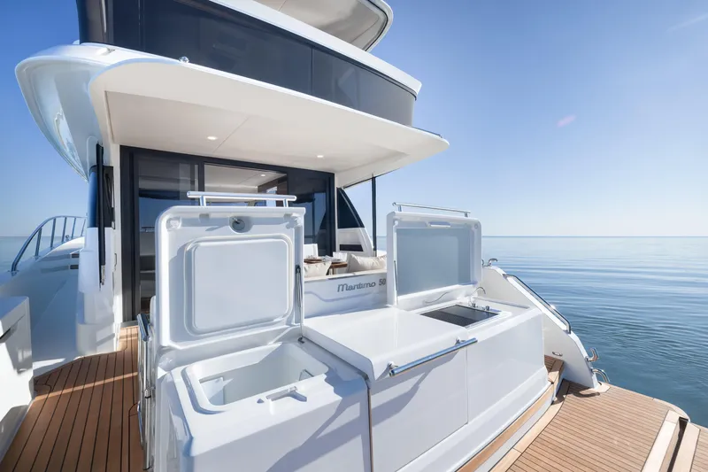 Slide: The Image of 2026 Maritimo M50 yacht deck with open storage compartments, overlooking calm ocean waters. - 5