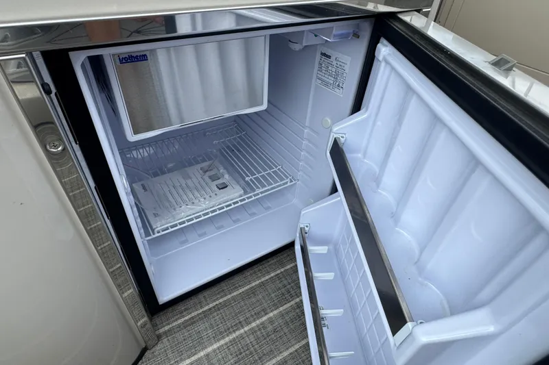 Slide: The Image of Open refrigerator on 2023 Harris Grand Mariner 250 boat, showcasing interior storage space. - 24