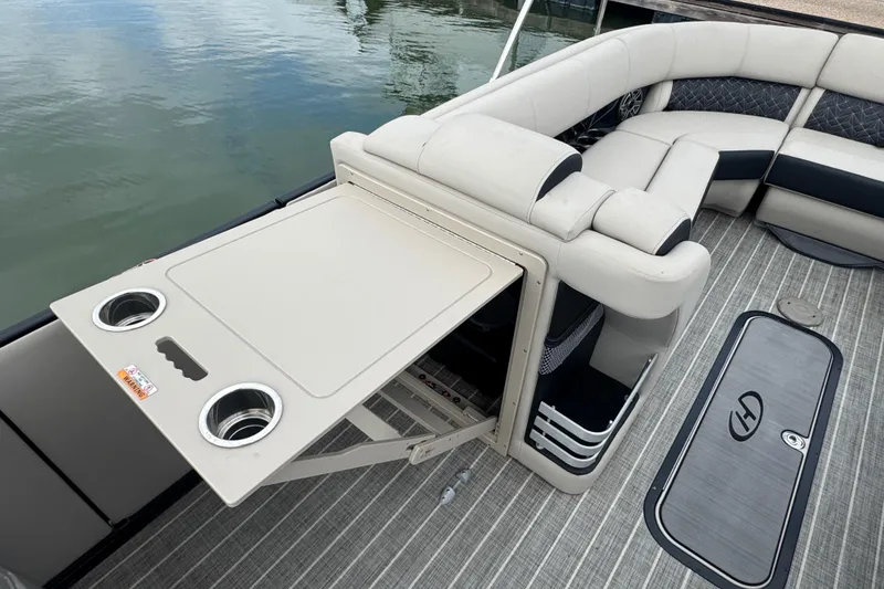 Slide: The Image of 2023 Harris Grand Mariner 250 boat interior with seating and foldable table by the water. - 25