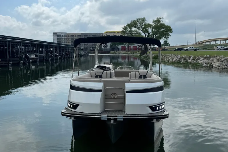 Slide: The Image of 2023 Harris Grand Mariner 250 pontoon boat docked on a calm lake under cloudy skies. - 4
