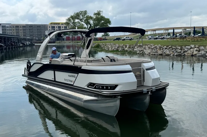 Slide: The Image of 2023 Harris Grand Mariner 250 pontoon boat on a calm lake near a park. - 5
