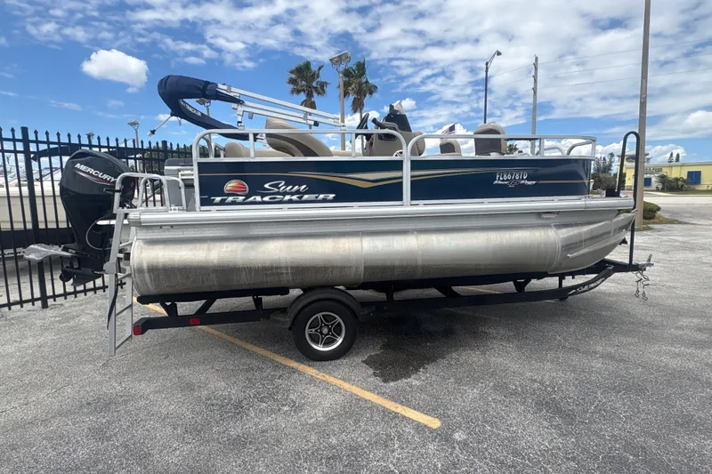 The Image of 2022 Sun Tracker Bass Buggy 16 XL Select pontoon boat on trailer, parked outdoors. - 1