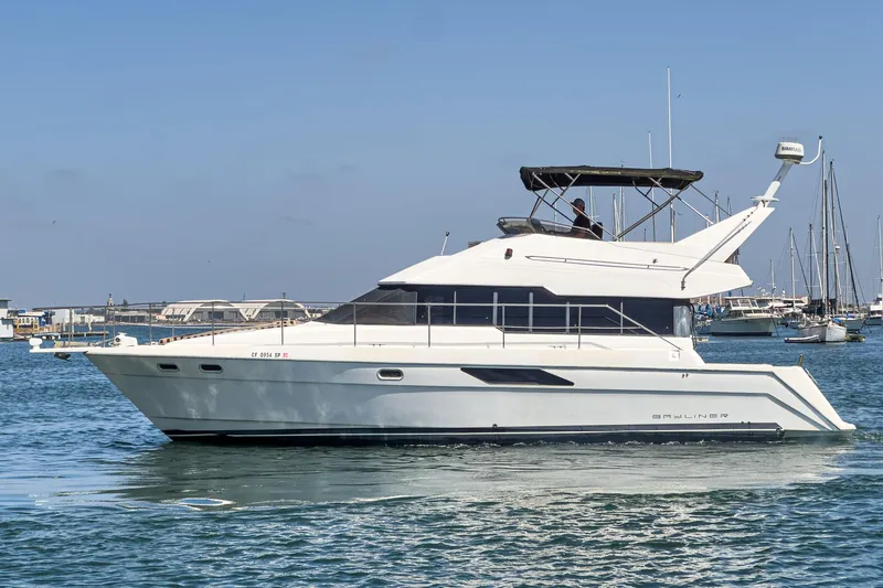 Slide: The Image of 1992 Bayliner 4388 yacht cruising in a marina under clear blue skies. - 3