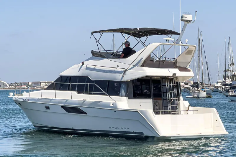 Slide: The Image of 1992 Bayliner 4388 yacht cruising in a marina with clear skies and calm waters. - 5