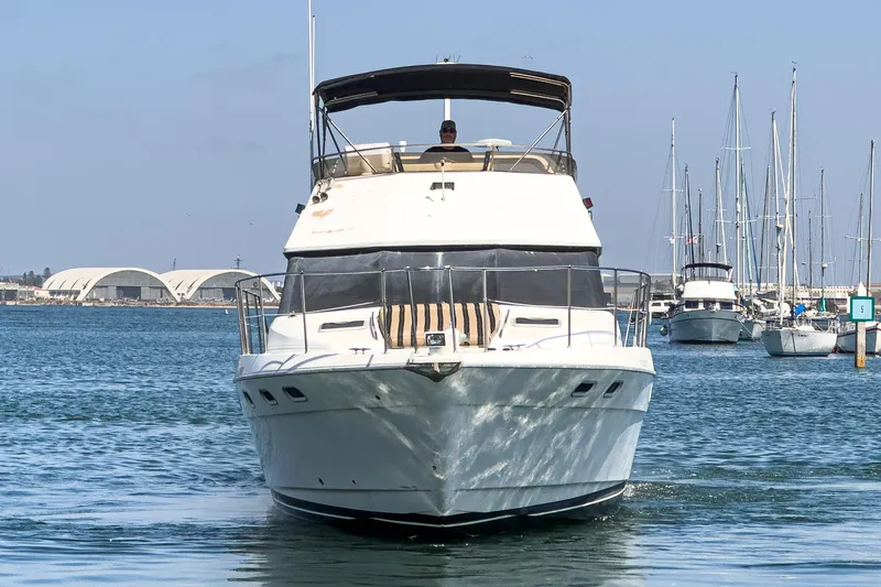 Slide: The Image of 1992 Bayliner 4388 yacht cruising in a marina with sailboats in the background. - 7