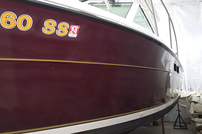 Slide: The Image of 2005 Tiara 290 Coronet boat with maroon hull and yellow stripe in storage. - 2