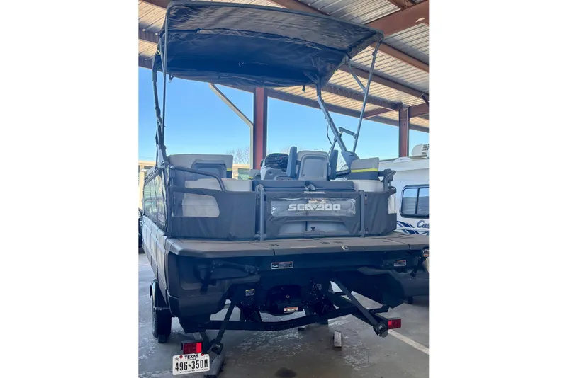 Slide: The Image of 2024 Sea-Doo Switch Cruise Limited 21 pontoon boat in storage, rear view. - 3