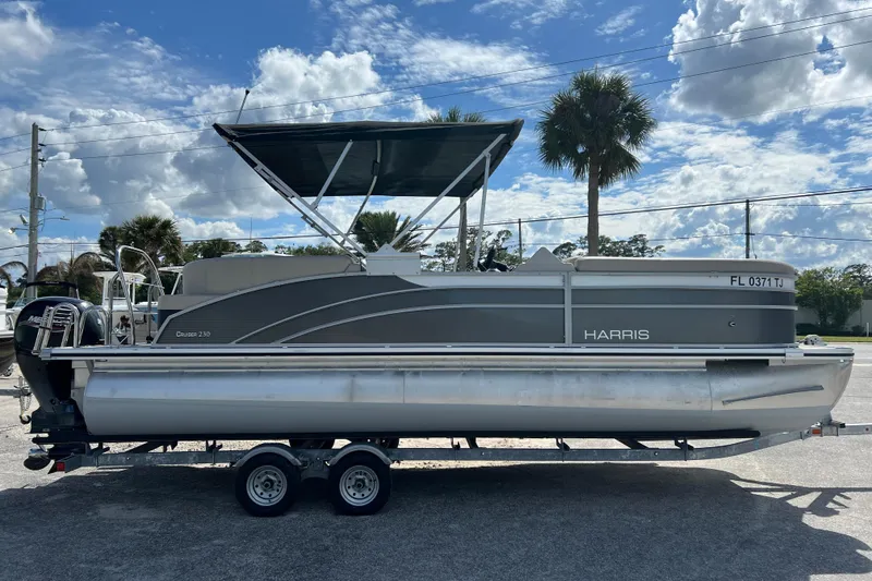 The Image of 2023 Harris Cruiser 230 pontoon boat on trailer under blue sky. - 1