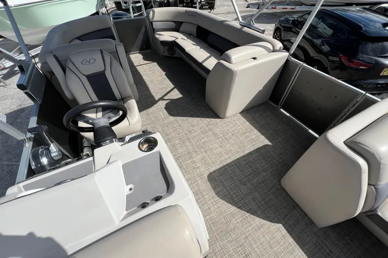 Slide: The Image of 2023 Harris Cruiser 230 pontoon boat interior with plush seating and steering console. - 10