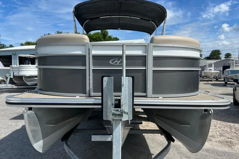 Slide: The Image of 2023 Harris Cruiser 230 pontoon boat on trailer, under clear blue sky. - 3
