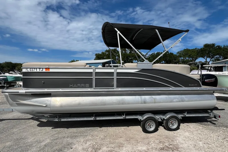Slide: The Image of 2023 Harris Cruiser 230 pontoon boat on trailer under blue sky. - 5