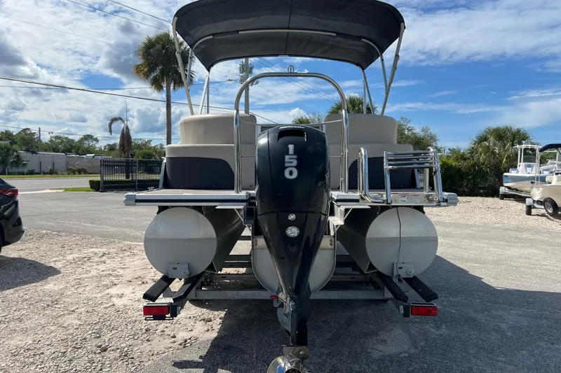 Slide: The Image of 2023 Harris Cruiser 230 pontoon boat with 150 HP engine, parked outdoors. - 7