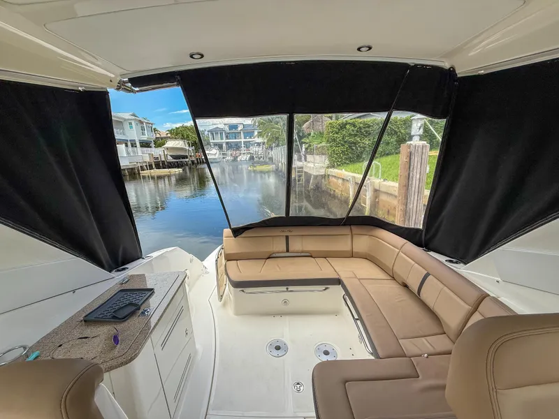 Slide: The Image of 2016 Sea Ray 350 Sundancer interior with tan seating and marina view. - 33