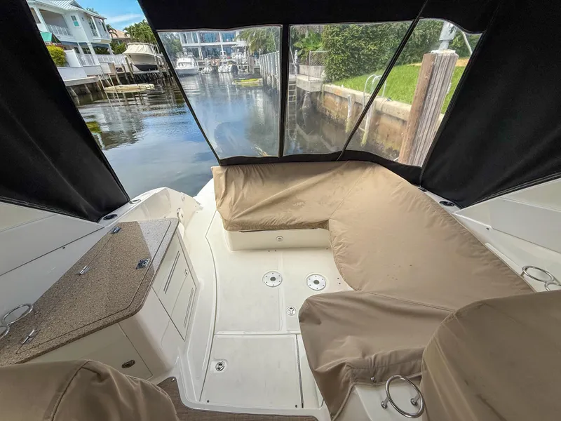 Slide: The Image of 2016 Sea Ray 350 Sundancer interior with seating, docked in a serene canal setting. - 35