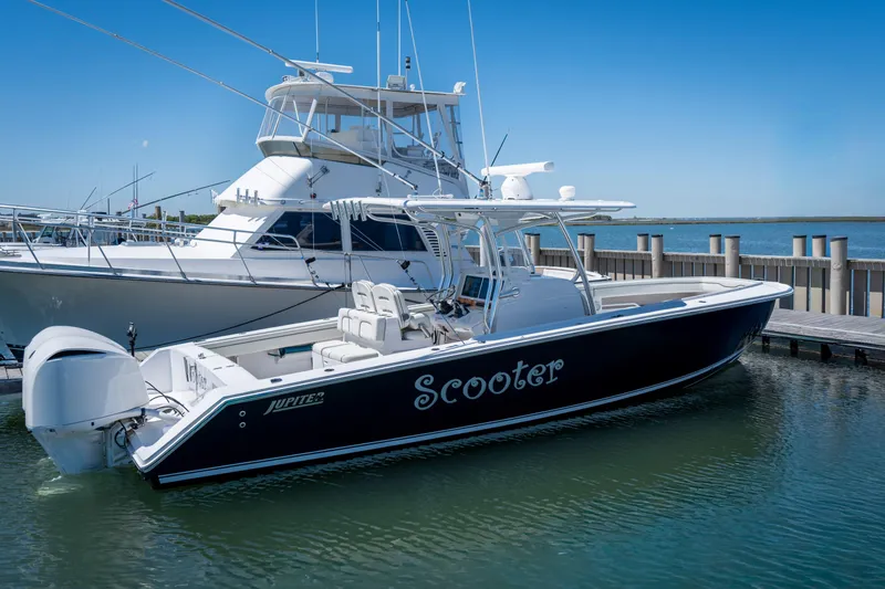 The Image of 2013 Jupiter 34 FS boat named "Scooter" docked in a marina under clear blue skies. - 0
