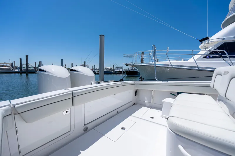 Slide: The Image of 2013 Jupiter 34 FS boat interior with dual engines, docked in a marina under clear blue sky. - 12