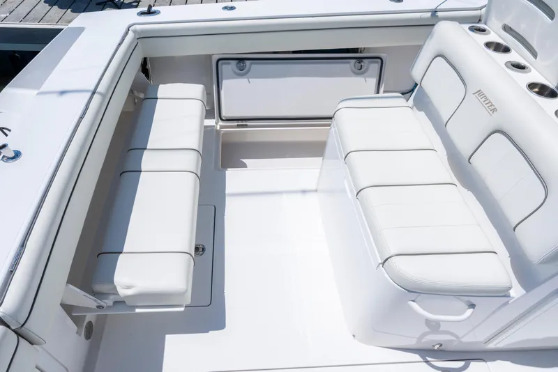 Slide: The Image of 2013 Jupiter 34 FS boat interior with white cushioned seating and storage compartments. - 14