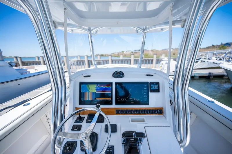 Slide: The Image of 2013 Jupiter 34 FS boat dashboard with navigation screens and steering wheel at marina. - 5