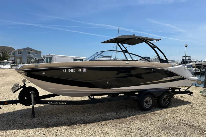 The Image of 2016 Scarab 255 H.O. Platinum boat on trailer, parked in marina under clear sky. - 0